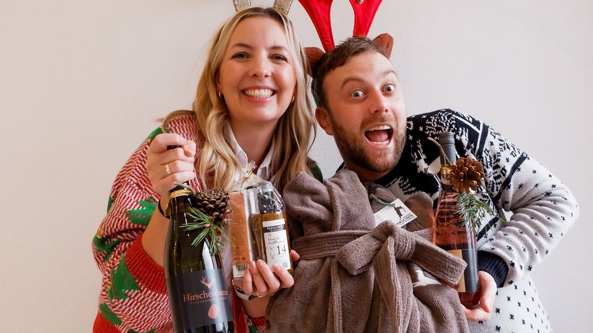 Eco-friendly hotel in Germany with Hirschenmanufaktur Happy couple wearing reindeer antlers holding gift bottles and a blanket