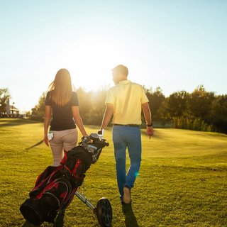 Gasthof Parsberg: Ein Gruß an den guten Geschmack Paar geht auf Golfplatz mit Golftasche bei sonnigem Wetter