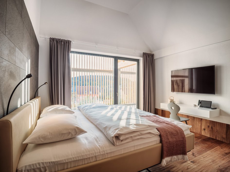 Leistungen und Preise für Tagungen und Konferenzen Modernes Schlafzimmer mit großem Bett, Fensterfront und Wandfernseher