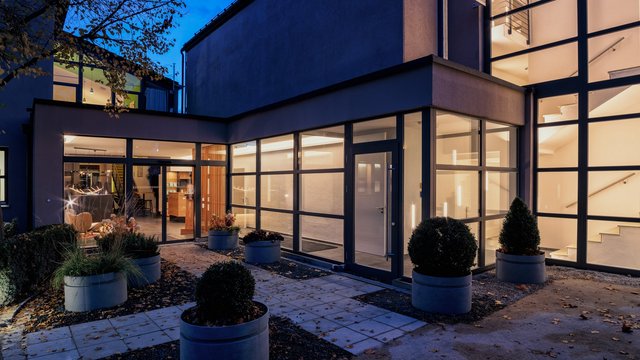 Romantik Hotel Hirschen: Blog Modernes Gebäude mit Glasfassade und beleuchteter Treppe bei Nacht