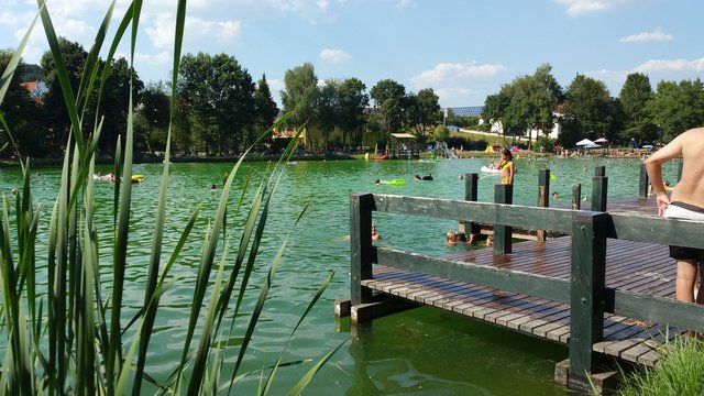 Romantik Hotel Hirschen: Blog Menschen baden in einem natürlichen See mit Holzsteg bei sonnigem Wetter