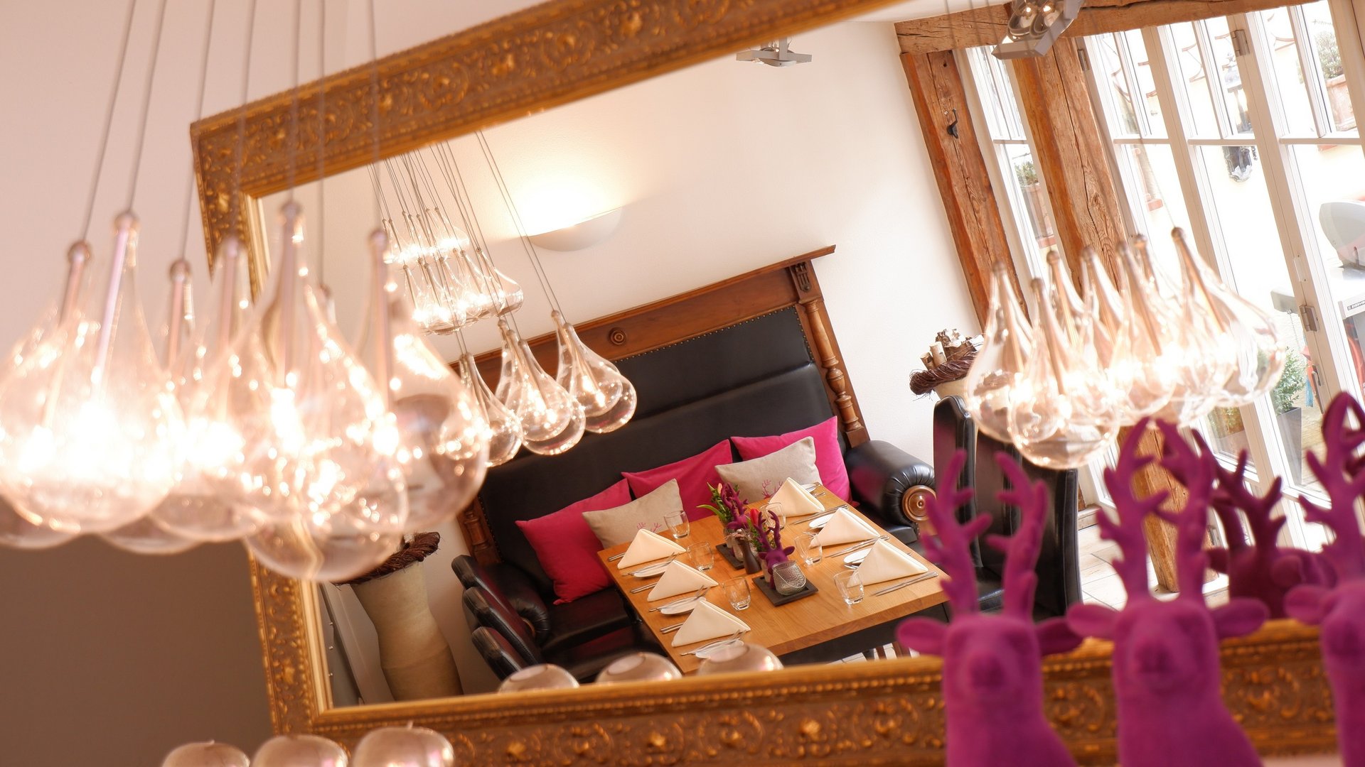 Romantik Hotel Hirschen: Blog Spiegelbild eines gedeckten Tisches mit hängenden Glühlampen und rosa Dekorationen