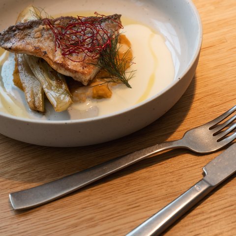 Romantik Hotel Hirschen: Gastgeber & Werte Gebratener Fisch mit Gemüse und Sauce auf einem weißen Teller