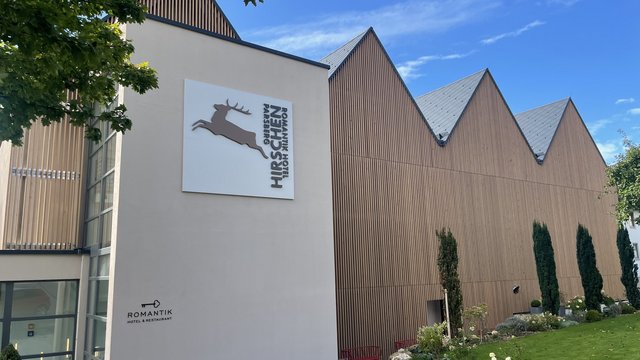 Romantik Hotel Hirschen: Blog Außenansicht vom Romantik Hotel Hirschen mit brauner Holzfassade und grünem Garten