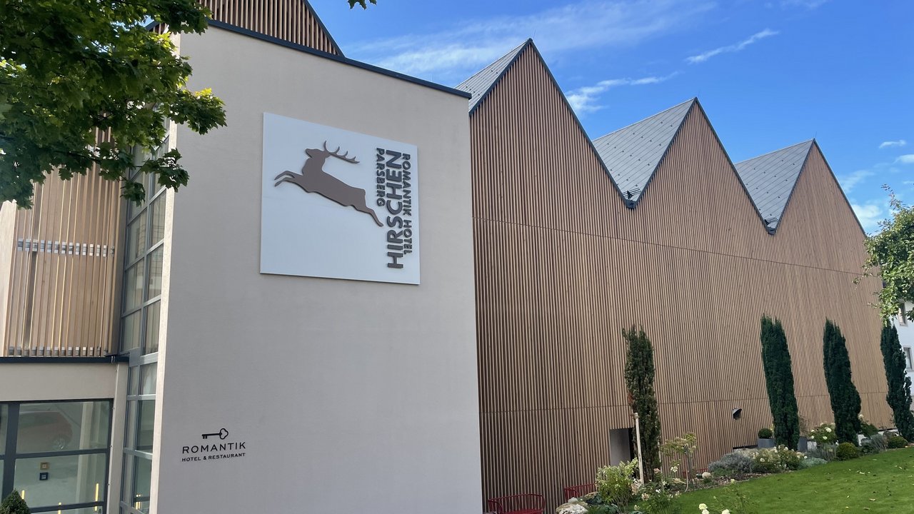 Außenansicht vom Romantik Hotel Hirschen mit brauner Holzfassade und grünem Garten