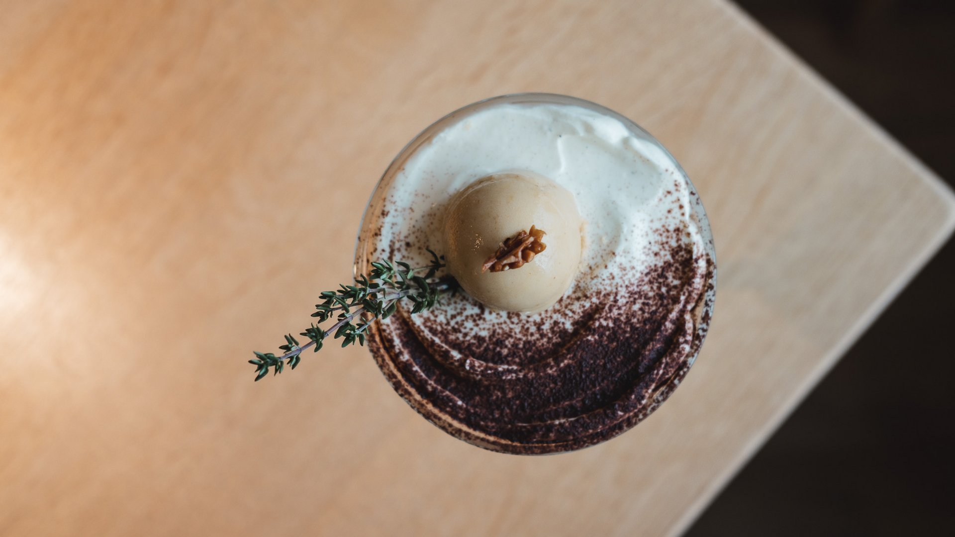 Romantik Hotel Hirschen: cuisine Dessert with whipped cream, cocoa powder, caramel ice cream, and thyme sprig
