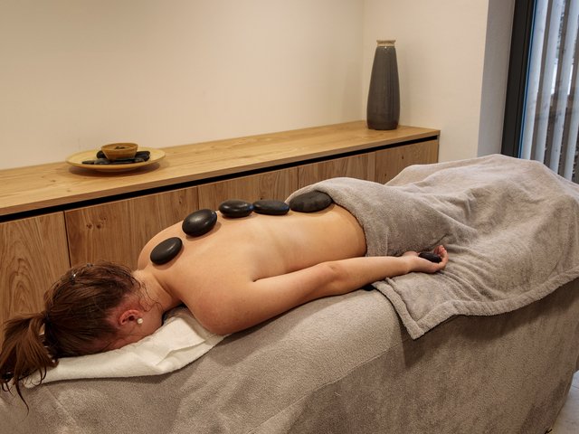 Home Woman receiving hot stone massage on back in peaceful spa room