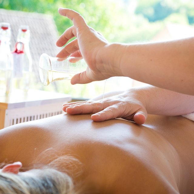 Revel in anticipation Massage oil being poured on the back of a person lying in a spa
