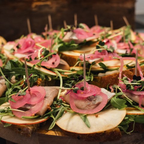 Brunch - das Langschläferfrühstück Fingerfood mit Brot, Apfelscheiben, Rucola, Fisch und Essigzwiebeln auf Holzplatte