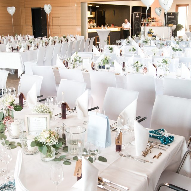 Hochzeitslocation Oberpfalz gesucht? Festlich dekorierter Veranstaltungsraum mit weißen Tischdecken und Stühlen