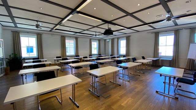 Romantik Hotel Hirschen: Blog Leerer Klassenraum mit weißen Tischen und schwarzen Stühlen und hölzernem Boden