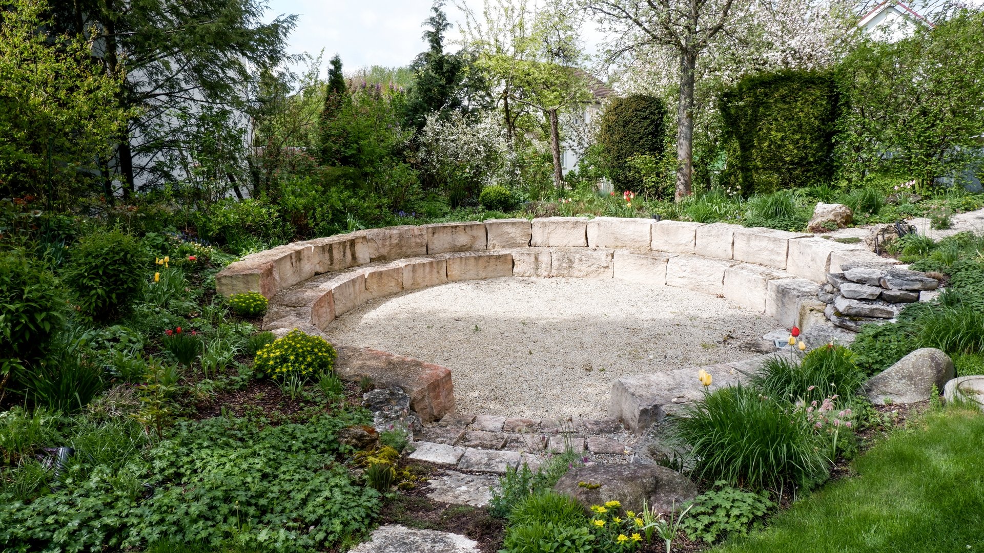 Leistungen und Preise für Tagungen und Konferenzen Steinrunde Bank im Garten umgeben von Blumen und Büschen