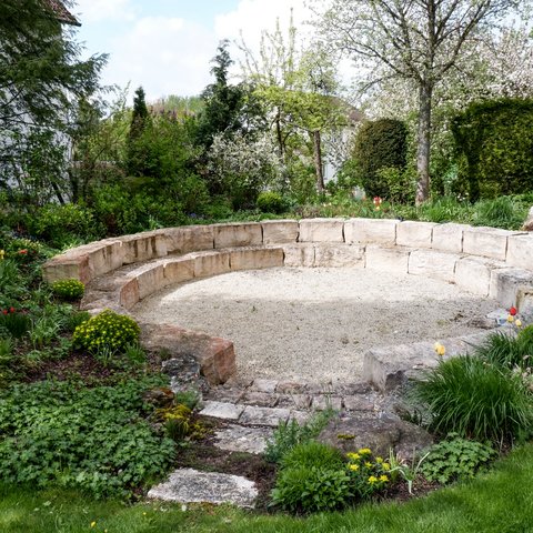 Tagungshotel Oberpfalz: Das Hotel für Deine Tagung Steinrunde Bank im Garten umgeben von Blumen und Büschen