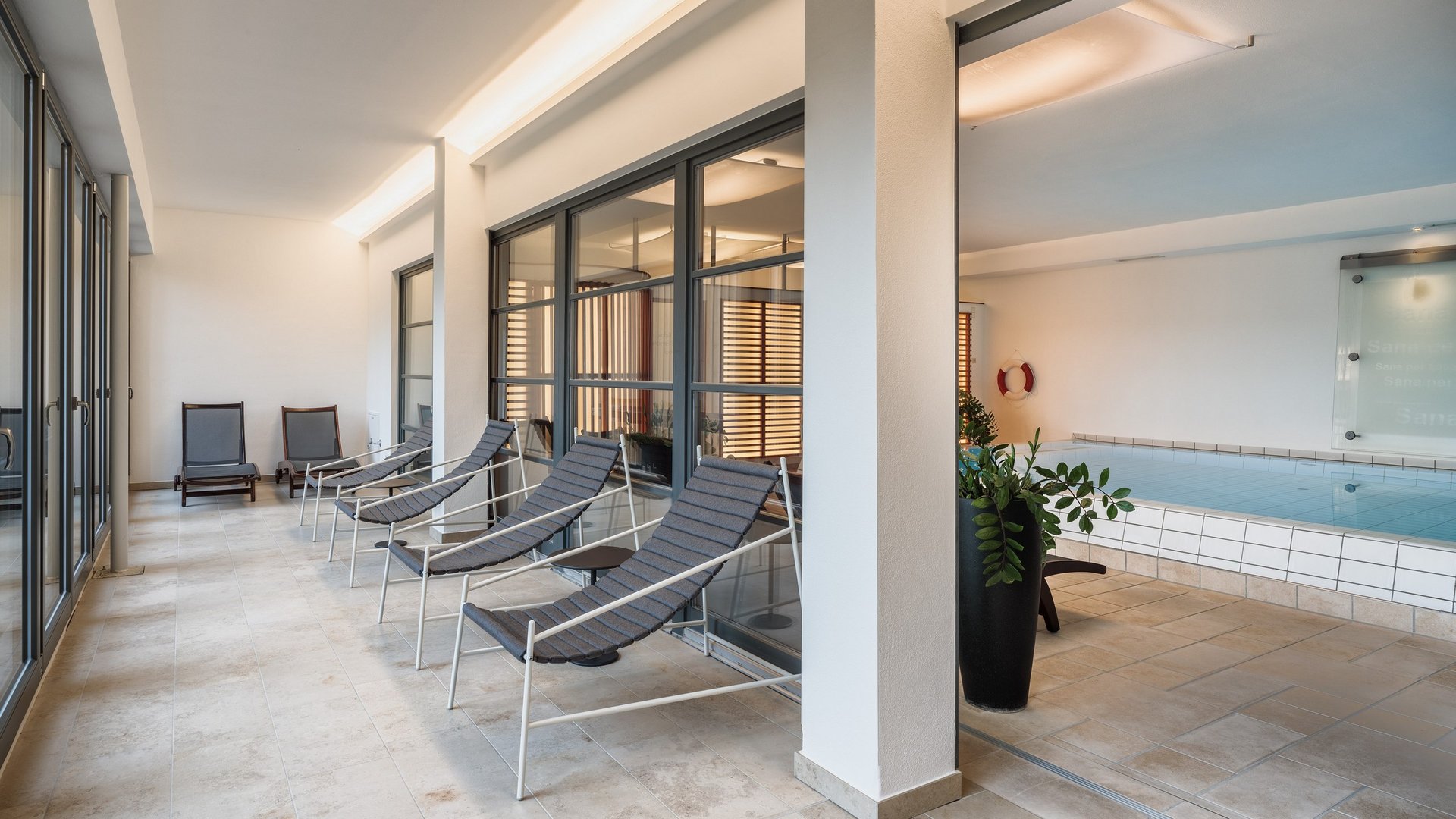 Entspannung in der Oberpfalz: Garten & Ruheräume Ruhebereich mit Liegestühlen neben einem Hallenbad in modernem Interieur