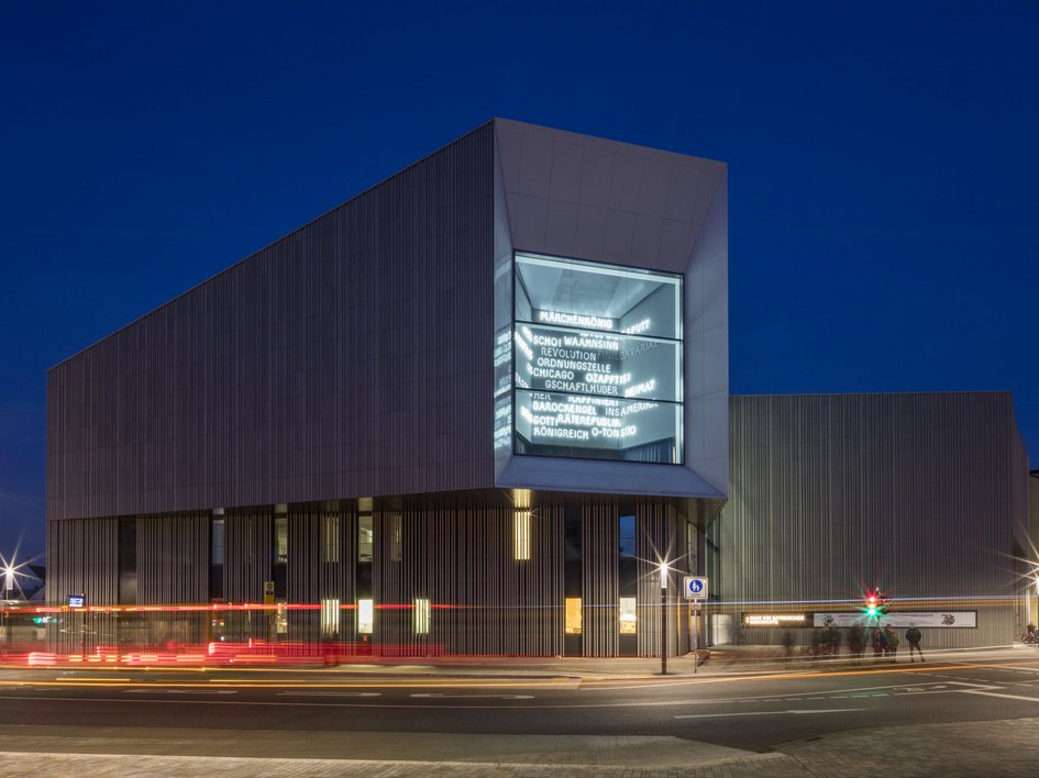 Hotels in Regensburg und Umgebung: kultur-trächtig! Modernes Gebäude bei Nacht mit beleuchteten Wörtern im großen Fenster