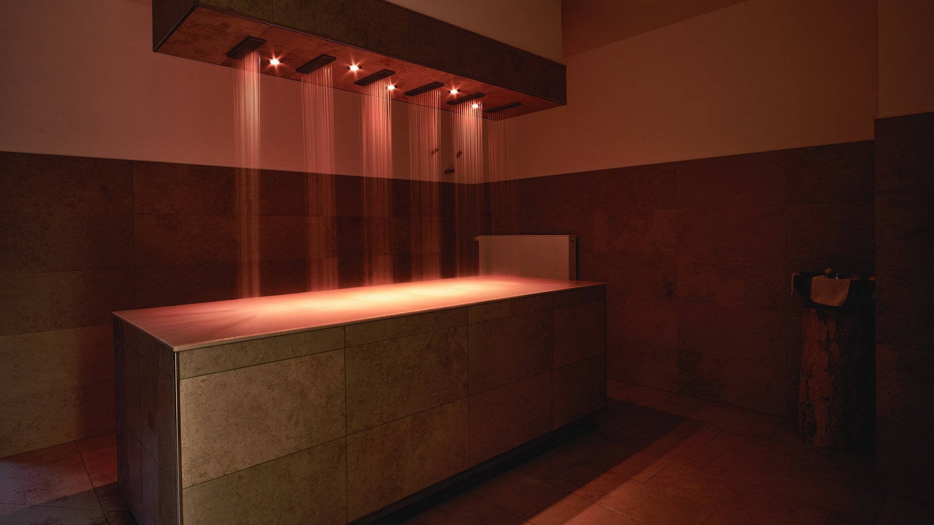 Wellnesshotel in der Oberpfalz: schwitzen & schwimmen Wellnessraum mit beleuchtetem Wasserstrahl über rechteckigem Becken