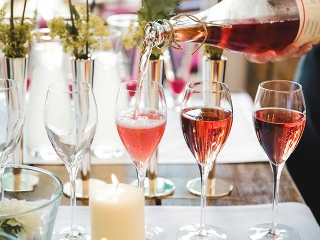 Romantik Hotel Hirschen: Bildergalerie Roséwein wird in mehrere Sektgläser auf einem dekorierten Tisch eingeschenkt