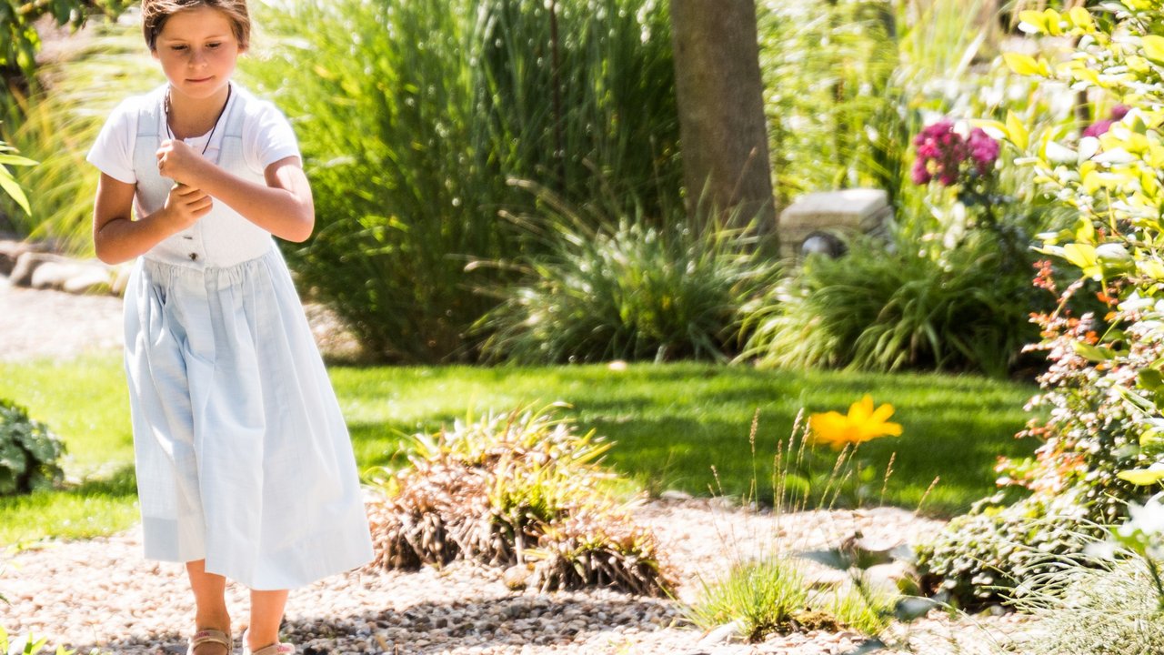 A girl in traditional dress walking on a gravel path in the garden