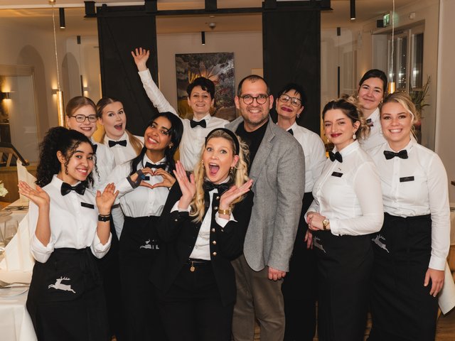 Romantik Hotel Hirschen: Bildergalerie Fröhliches Team aus Kellnern und Manager in Restaurant mit schwarzen Schürzen und Fliegen