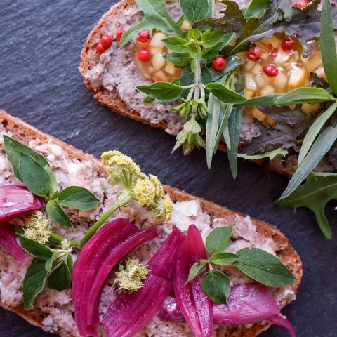 Kulinarik & Genuss in der Oberpfalz Belegtes Brot mit Kräutern, roten Zwiebeln und Pfefferkörnern auf dunkler Unterlage