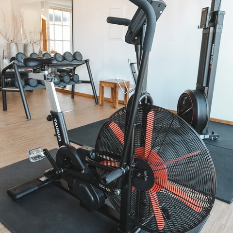 Fitnessraum Air resistance bike in gym next to dumbbells