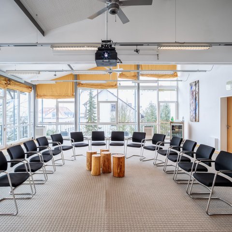 Looking for somewhere for conferences in Bavaria? Bright meeting room with chairs in a circle and wooden logs as tables