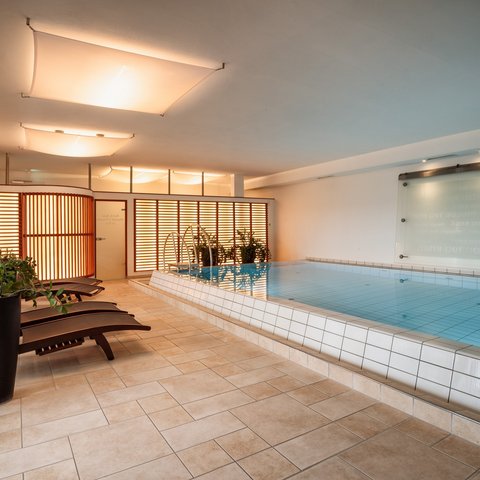 Your enquiry at Romantik Hotel Hirschen Indoor pool with lounge chairs and plants in a modern wellness area