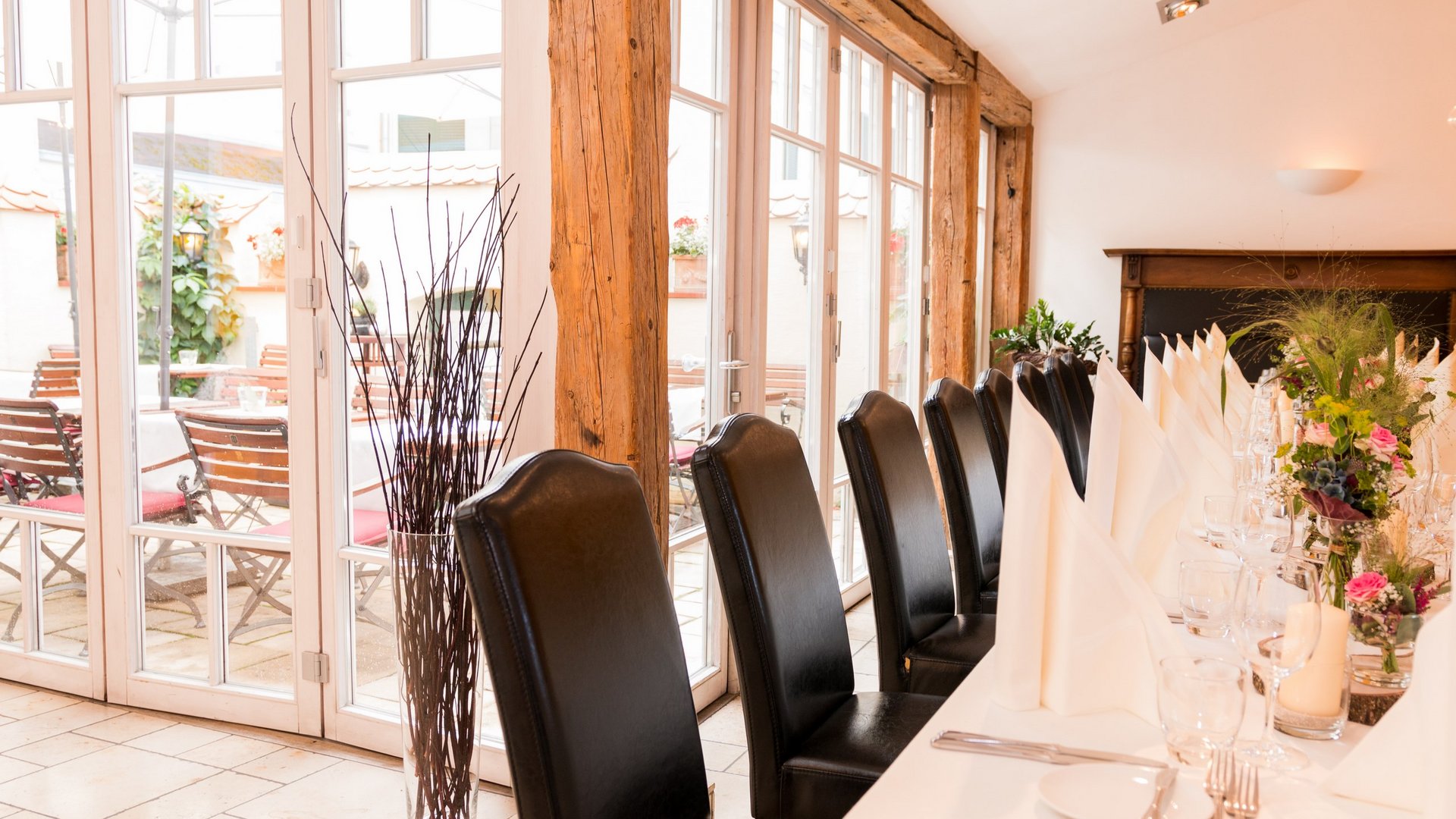 Hochzeitslocation Oberpfalz gesucht? Elegantes, gedecktes Restaurant mit schwarzem Lederstuhl und weißen Servietten