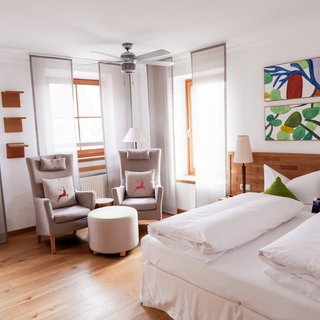 Social Media Wall: Exklusive Einblicke ins Revier Helles Hotelzimmer mit Doppelbett, zwei Sesseln und abstrakter Kunst an der Wand