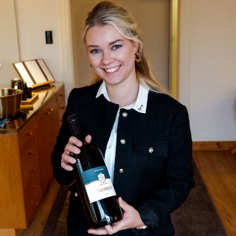 Guesthouse in Parsberg: A salute to great taste Woman smiling holding a bottle of Saffredi red wine indoors
