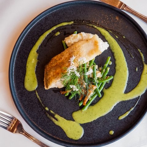 Guesthouse in Parsberg: A salute to great taste Pan-seared fish fillet with green beans and green sauce on a black plate