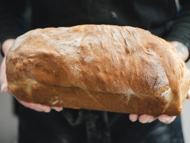 Romantik Hotel Hirschen: Bildergalerie Person hält frisches, großes Laib Brot in den Händen