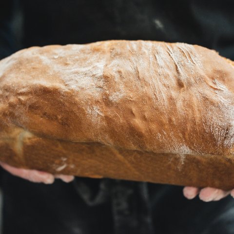 Guesthouse in Parsberg: A salute to great taste Person holding a large fresh loaf of bread in hands