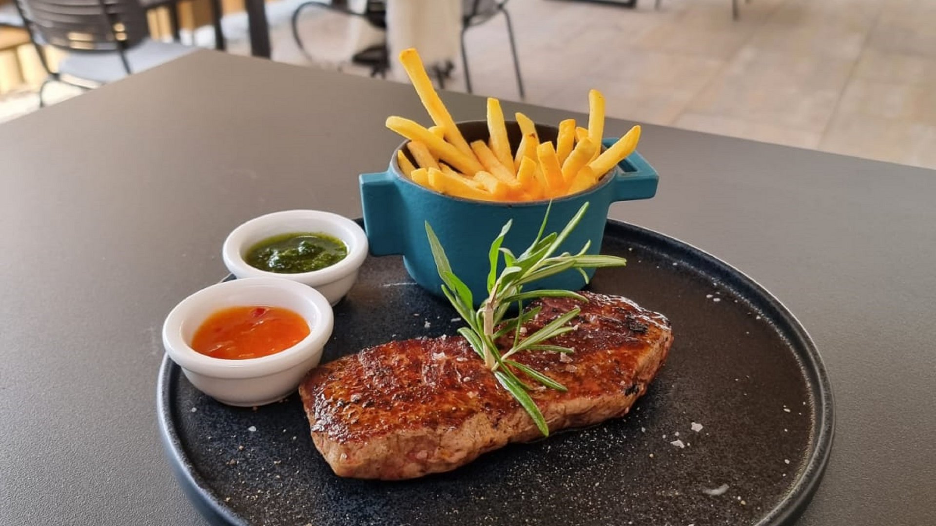 Beer garden in Parsberg: HirschenBlobb Steak with fries and two sauces on black plate in a modern restaurant