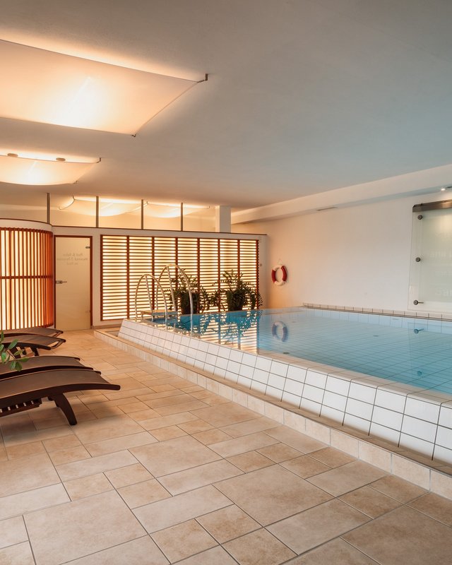 Hotel in Upper Palatinate: Get a breath of holiday air! Indoor swimming pool with lounge chairs and plants in bright room