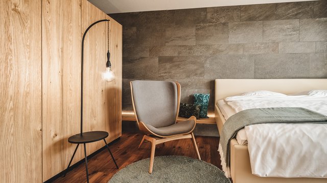 Angebote aus dem Romantik Hotel Hirschen Modern eingerichtetes Schlafzimmer mit grauem Stuhl und Holzschrank