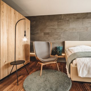 Wellnesshotel in Parsberg mit Spa, Genuss und stilvollen Zimmern. Modern eingerichtetes Schlafzimmer mit grauem Stuhl und Holzschrank