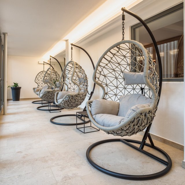 Wellnesshotel in der Oberpfalz: schwitzen & schwimmen Vier hängende Korbsessel mit Kissen in modernem, hellem Raum