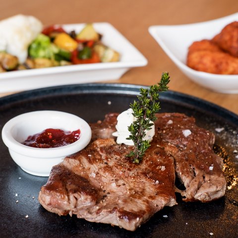 Beer garden in Parsberg: HirschenBlobb Grilled steak with herb butter, sauce, and vegetables on plates