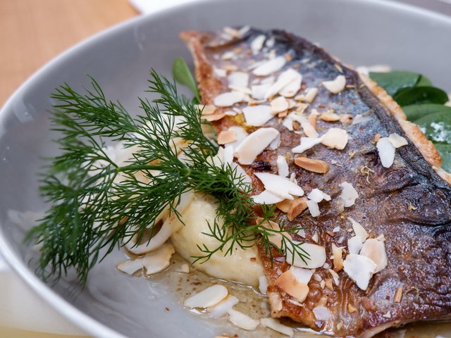 Romantik Hotel Hirschen: Bildergalerie Gebratener Fisch mit Mandelblättchen und Dill auf einem weißen Teller