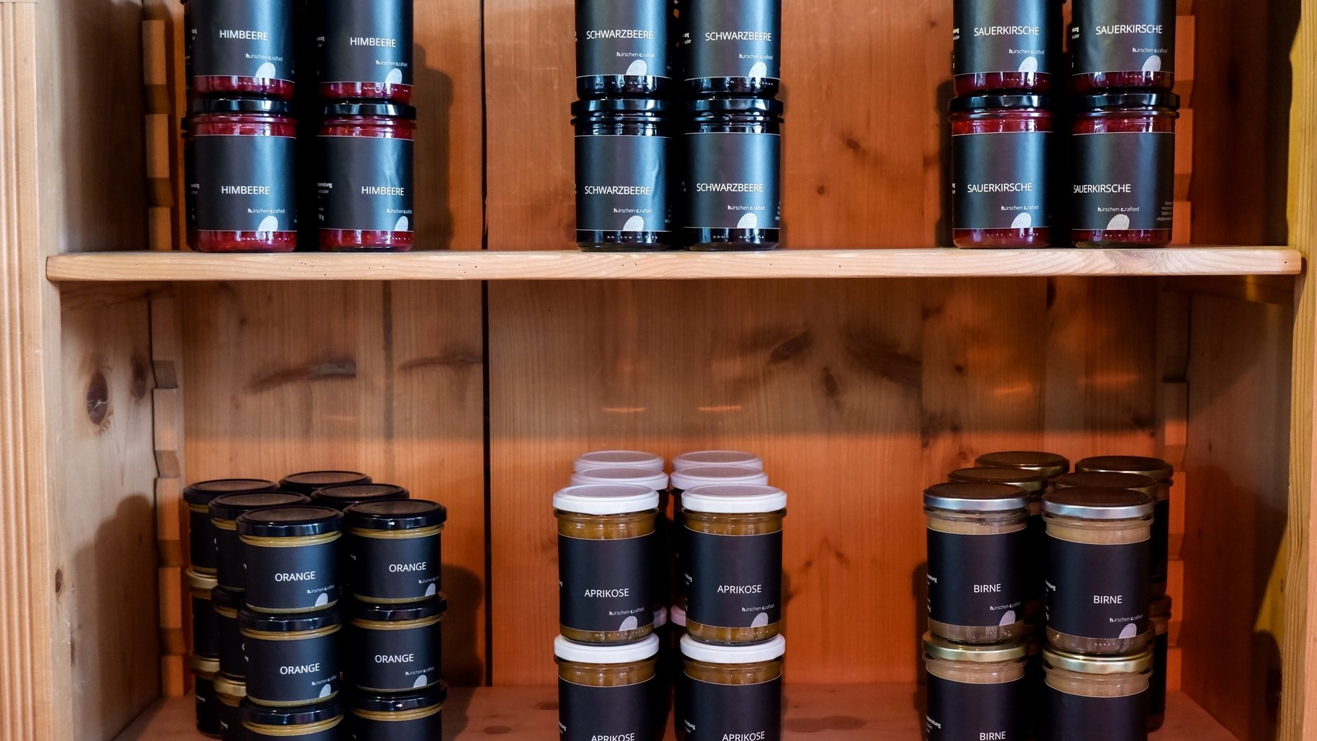 Nachhaltiges Hotel in Bayern mit Hirschenmanufaktur Verschiedene Marmeladengläser in einem Holzregal sortiert