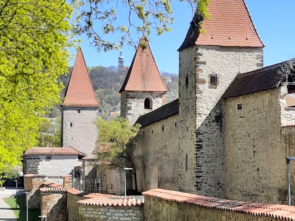 Hotels in Regensburg und Umgebung: kultur-trächtig! Historische Stadtmauer mit Türmen und roten Ziegeldächern an einem sonnigen Tag