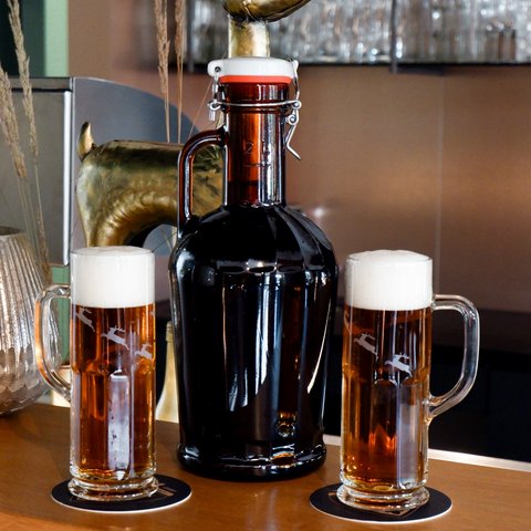 Hirschenblobb: Our bar Two beer mugs and a brown beer bottle on a bar counter
