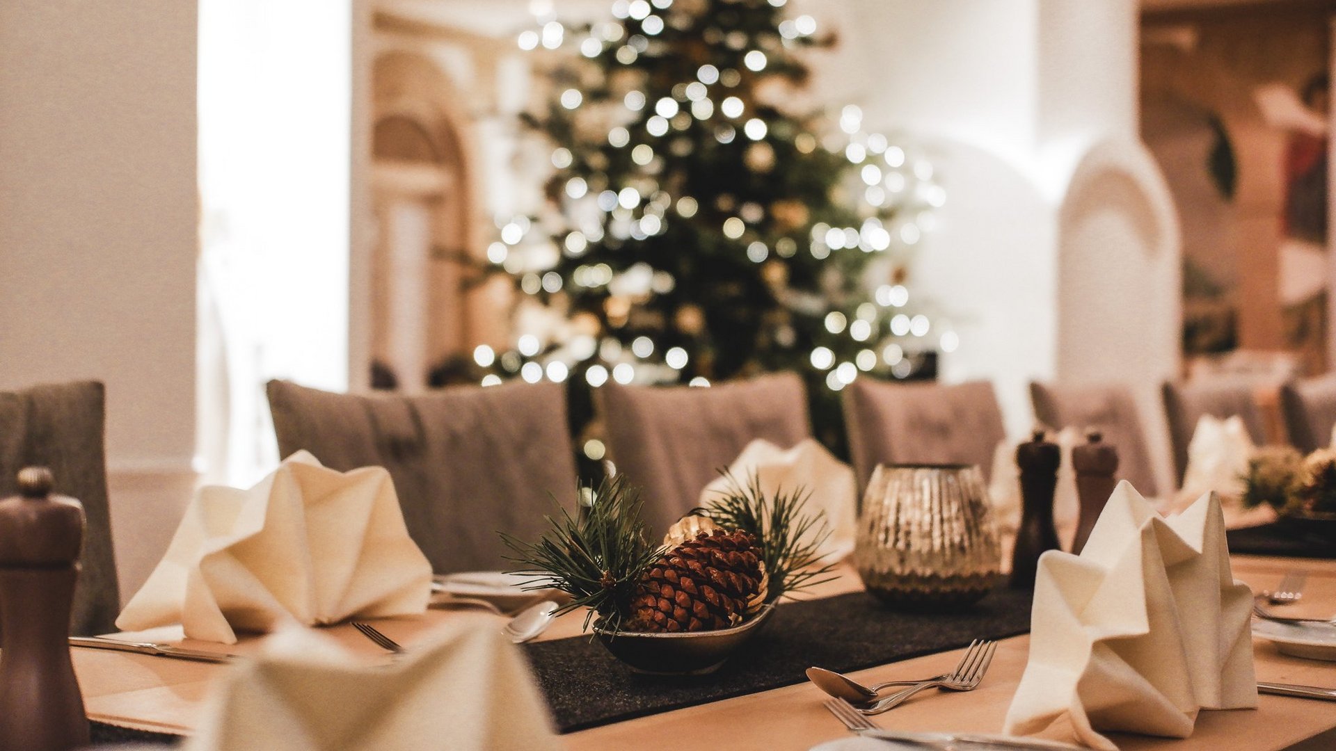 Gasthof Parsberg: Ein Gruß an den guten Geschmack Weihnachtlich gedeckter Tisch mit Tannenzapfen und Weihnachtsbaum im Hintergrund