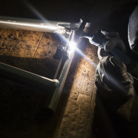 Looking for a hotel with bike rental in Bavaria? Gloved welder joining metal frame wearing protective helmet