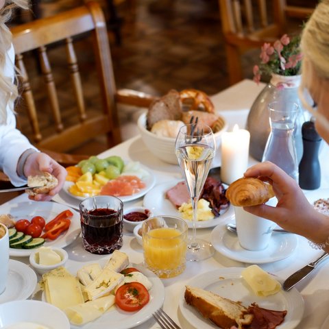 Romantik Hotel Hirschen: Frühstück Zwei Frauen genießen ein reichhaltiges Frühstück mit Gebäck und frischem Obst