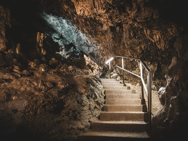 Romantik Hotel Hirschen: Bildergalerie Beleuchtete Steintreppe mit Geländer in einer Höhle mit Felswänden