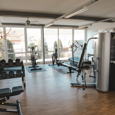 Fitnessraum Bright gym room with workout machines and large windows