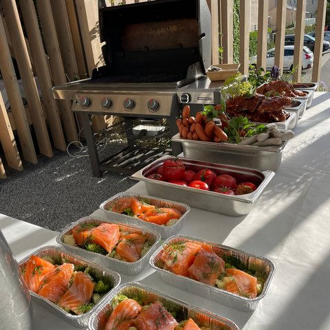 Beer garden in Parsberg: HirschenBlobb Grill and aluminum trays with salmon, tomatoes, and sausages on table