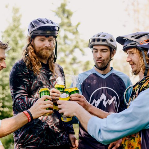 Looking for a hotel with bike rental in Bavaria? Five men wearing bike helmets cheers with canned drinks in the forest